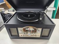 Front view of Crosley CR6001A record player with lid open, showing turntable and tonearm.