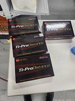 Four boxes of Orbiter Ti-Pro Distance golf balls, unopened and partially opened showing full and partial contents