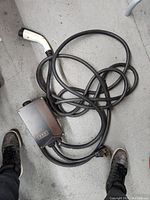 Full view of the JuiceBox EV charger unit lying coiled with cable on a concrete floor.