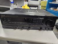 Front view of Kenwood KR-V6020 audio-video stereo receiver showing control knobs, buttons, and input options.