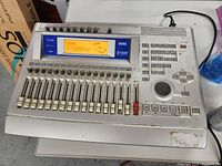 Full front view of the Korg D1600 digital recording studio showing fader controls, keypad, display, and function buttons.