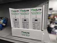Display box with multiple MaxLite Energy Saving Power Strip boxes vertically arranged on a shelf.