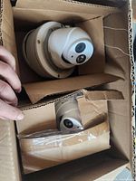 Two LB7307 security cameras packed in cardboard boxes, one camera is fully visible and the other partially visible.