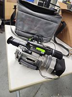 Camcorder placed on table next to grey bag