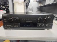 Front view of Technics SA-AX720 AV control stereo receiver showing power button, knobs for mode and volume, and digital display.
