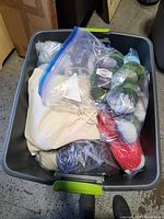Full tote container with assorted yarn skeins packed inside, showing multiple colors and packaging types.