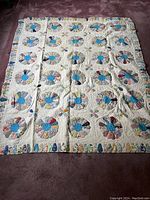 Full view of the quilt laid flat showing entire pattern of Dresden Plate blocks and patchwork border.