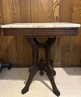 Full side view of antique Victorian table showing removable marble top and carved walnut base with curved legs.