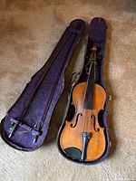 Full view of the violin in its open case along with the bow, showing overall condition and presentation.