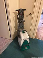 Front right angle view of the Bissell Big Green carpet cleaner showing the tank, handle, and power cord.