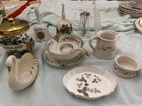 Wide view showcasing mini Lenox swan creamer and sugar cup, Wedgwood Wild Strawberry pin dish, glass stirrers, and collectible porcelain bells.