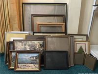 Photo showing all 15 assorted picture frames of various sizes mostly wood with glass fronts, some containing prints or artwork.