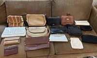 All 18 assorted purses and wallets arranged on couch including beaded and fabric bags
