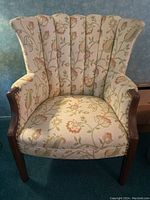 Full view of antique cream upholstered fan back chair showing floral fabric, dark wood legs, and overall condition.
