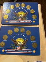 Two blue display cards showing circular gold-colored coins with U.S. Presidential profiles arranged in a circle around an eagle with a patriotic design