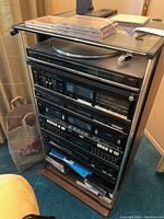 Full view of the vintage Fisher stereo system with record player top, tower cabinet with multiple audio components, and CDs on the top glass cover.