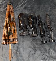Lot showing four carved dark hardwood East African figures and folded bamboo umbrella with wooden handle.