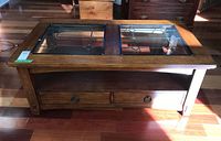 Front view of coffee table showing wood frame, glass inserts and drawers