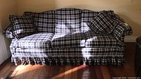 Front view of three seat plaid sofa with cushions and pillows, showing the overall design and condition.