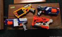 Photo showing four different Nerf toy guns arranged on a wooden table.