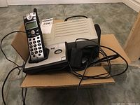 GE cordless handset and Norstar Meridian telecom device placed together on a cardboard box.