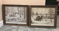 Two framed black and white C.M. Bowman prints depicting winter rural scenes is shown leaning against a wall by stairs.
