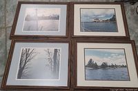 Four wooden framed photo prints arranged in a 2x2 layout on a tiled floor, showing serene water scenes with trees and buildings.