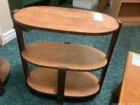 Full view of the oval wooden wall table with three shelves, showing wood grain and construction details