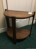 Full view of the wooden demilune wall table with semi-circular top and bottom shelf, showing overall structure and design.