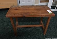 Top/side angle of small wooden table or bench showing water damage and marks on the surface and legs.