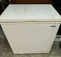 Front view of a white Uberhaus chest freezer showing some dirt on the top surface and the brand label on the top right corner of the front panel.