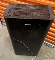 Front view of black Danby portable air conditioner showing the brand name and top control panel with dust covering.
