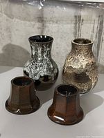 Four West German pottery items: two vases and two candleholders in earthy tones and textured glazes.