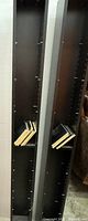 Photo showing two tall black media shelves side by side with adjustable slots seen from the side.