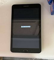 Front view of Samsung Galaxy Tab E powered on, displaying Samsung logo.