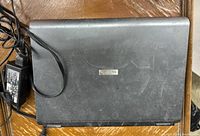 Top closed view of black Toshiba laptop with visible wear and Toshiba logo on top.