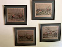 Four framed prints hung on a wall, each showing a hunting or equestrian scene with red-coated riders and hunting dogs.