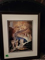 Framed print image showing surreal staircase with robed figures, framed with white and navy matting and dark brown frame