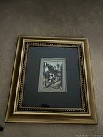 Full view of framed print showing a street scene with buildings and a street lamp, matted and framed in gold color frame with bead trim