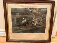 Framed vintage colored print titled 'The First Steeplechase on Record' showing detailed scene of horse race with jockeys in action.