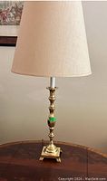 Lamp with gold-tone metal decorative column base and neutral beige tapered shade