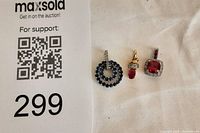 Three pendants displayed together next to auction sign