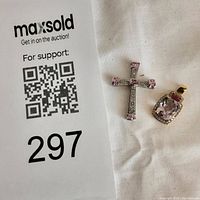 Both pendants laid on white cloth beside auction lot card