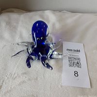 Blue glass octopus figurine with clear tentacles shown from front with maxsold tag