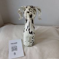 Front view of white and black spotted Dalmatian glass figurine on white surface.