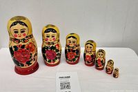 Full set of 7 Russian nesting dolls arranged from largest to smallest, with Maxsold card for scale
