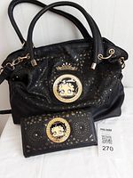 Black Betty Boop purse with matching wallet placed in front revealing front designs including cutouts and Betty Boop face medallions.