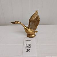 Front view of solid brass swan figurine with wings raised, showing overall shape and proportions