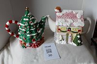 Both Christmas-themed ceramic tea pots together showing the tree and house designs