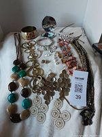 Full lot view showing all costume jewelry items spread on white fabric, including necklaces, bracelets, headband, and earrings.